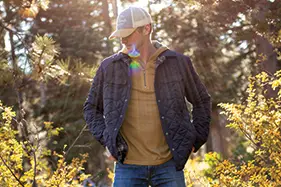 Man standing in front of wooded area during fall.