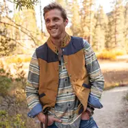 Man standing outdoors wearing vest.