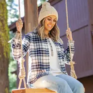 Woman sitting in swing outside cabin during fall.